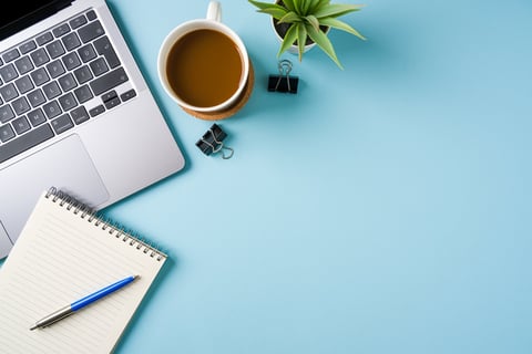 Coffee cup, laptop keyboard and stationery items on office desk